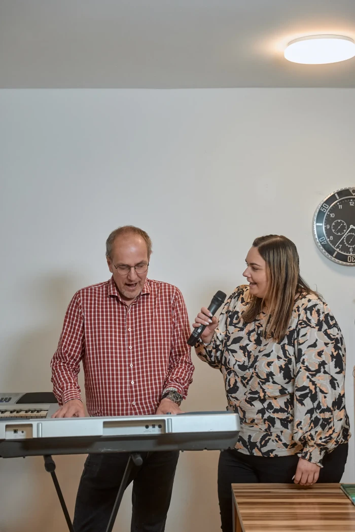 Ein Mann spielt Keyboard, während eine Frau mit Mikrofon daneben singt.