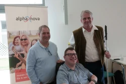 Drei Männer lächeln bei einer alpha-nova-Veranstaltung in die Kamera.